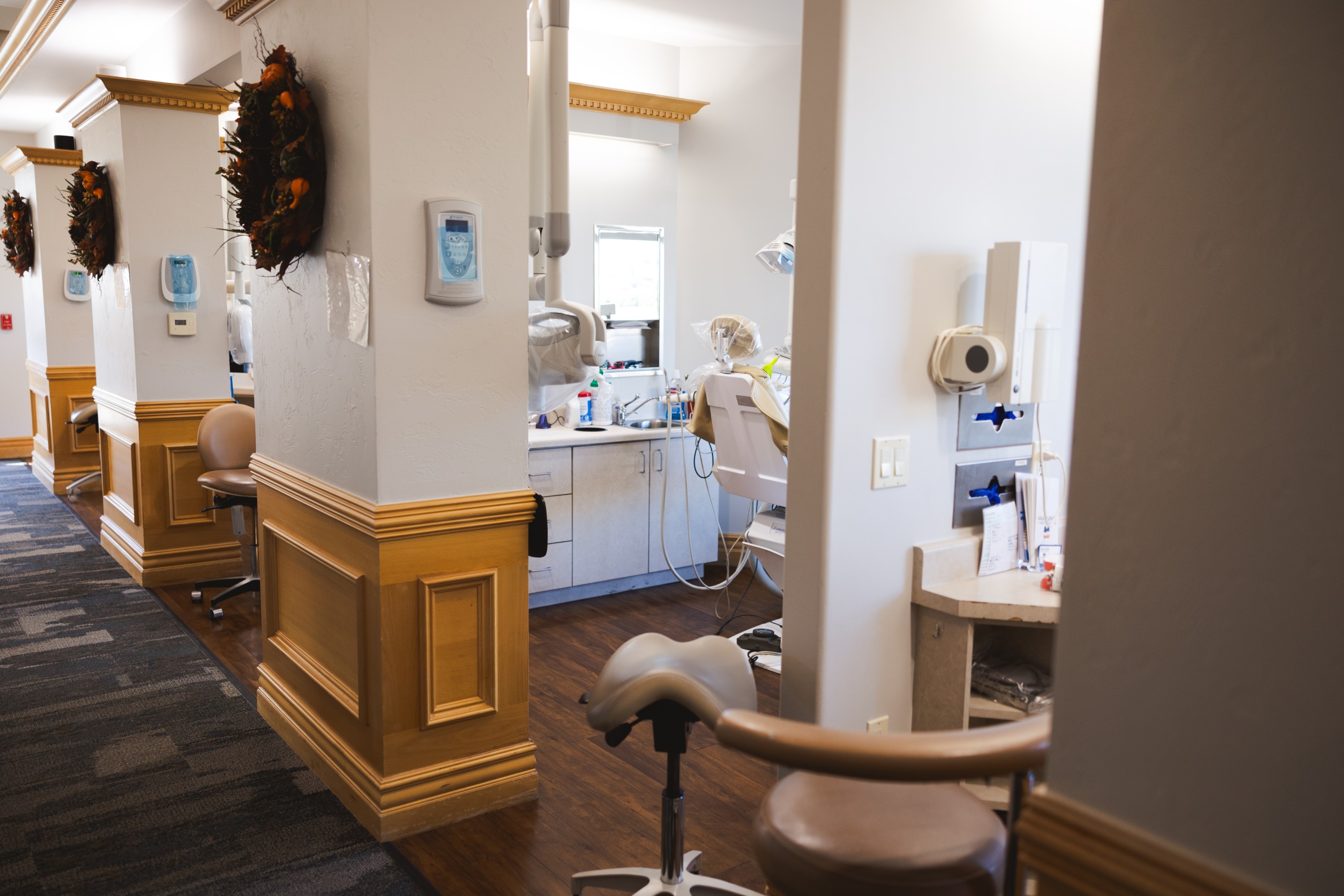Smiling dental receptionist sitting behind a clinic desk with a tooth model and pamphlets nearby.