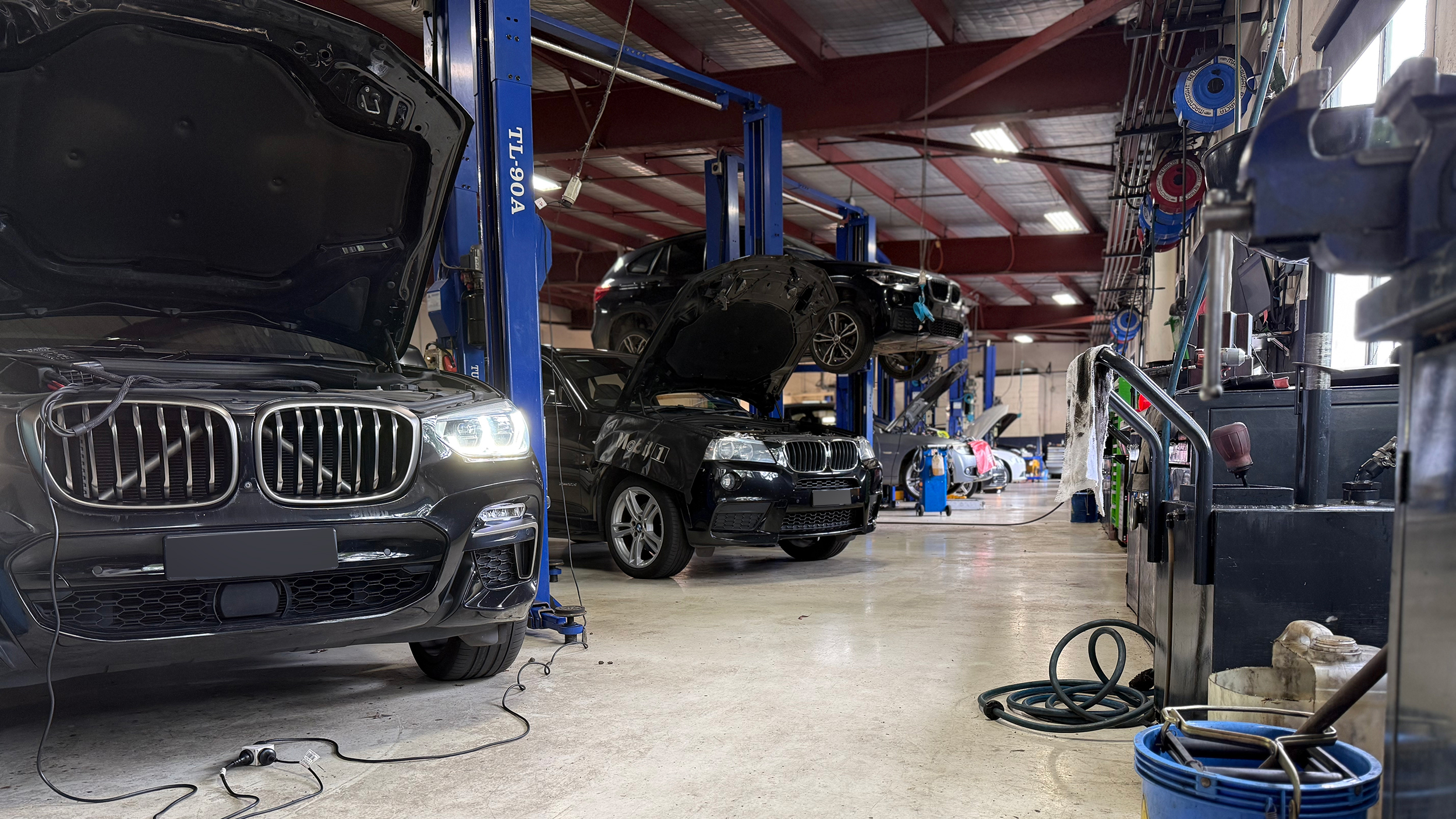 BMT Workshop with BMW SUVs being serviced, one raised on a lift
