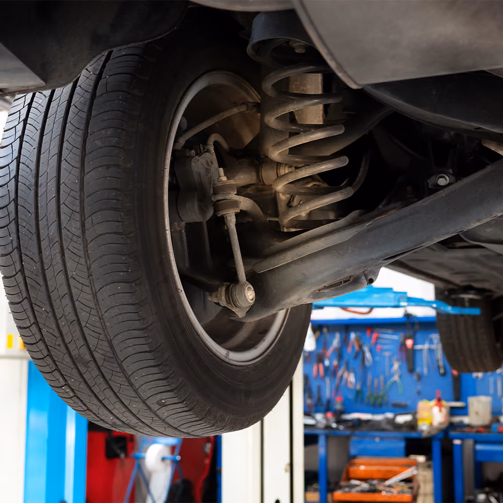 Technician adjusting suspension during wheel alignment