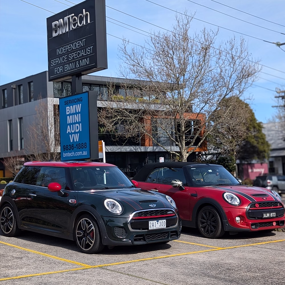 Two MINI vehicles parked outside the BM Tech workshop in Melbourne, with BM Tech service signage in the background.