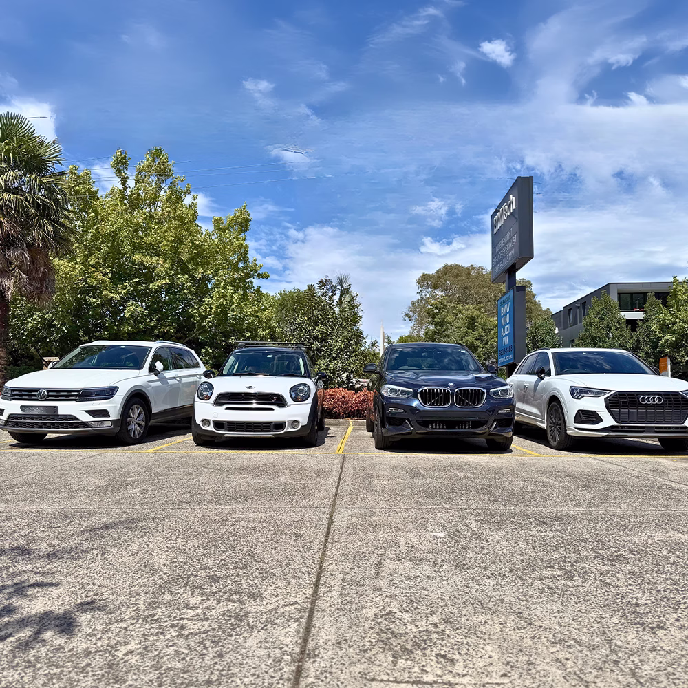Volkswagen, MINI, BMW and Audi vehicles parked side by side outside an automotive workshop.