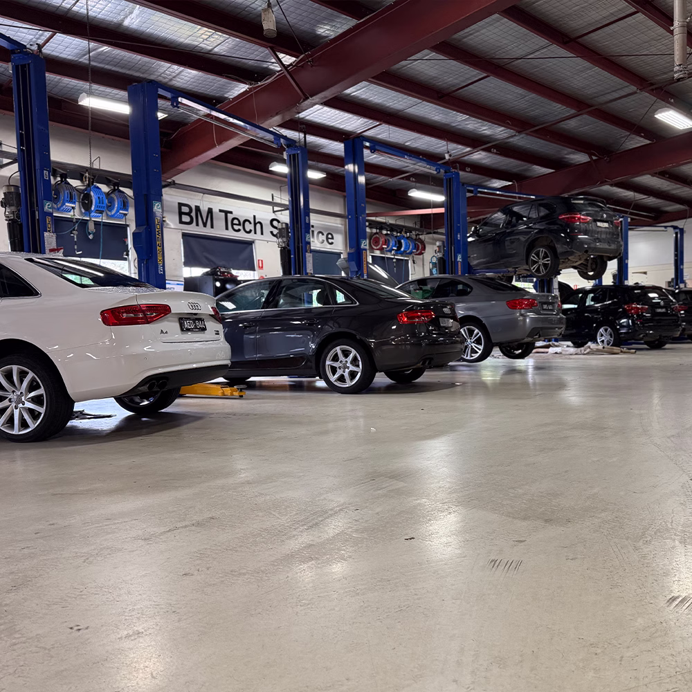Audi and BMW vehicles lined up for servicing inside the spacious BM Tech automotive workshop.