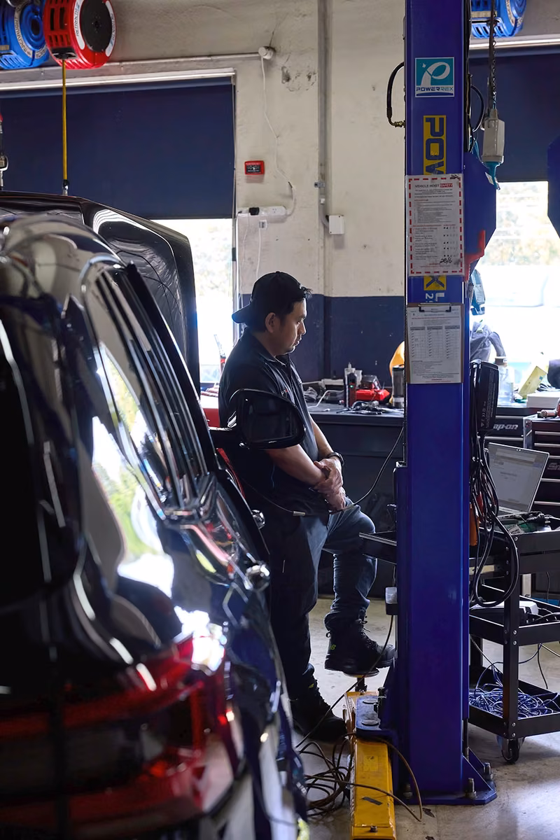 BMT Technician performing diagnostics beside a car in the BMT Workshop