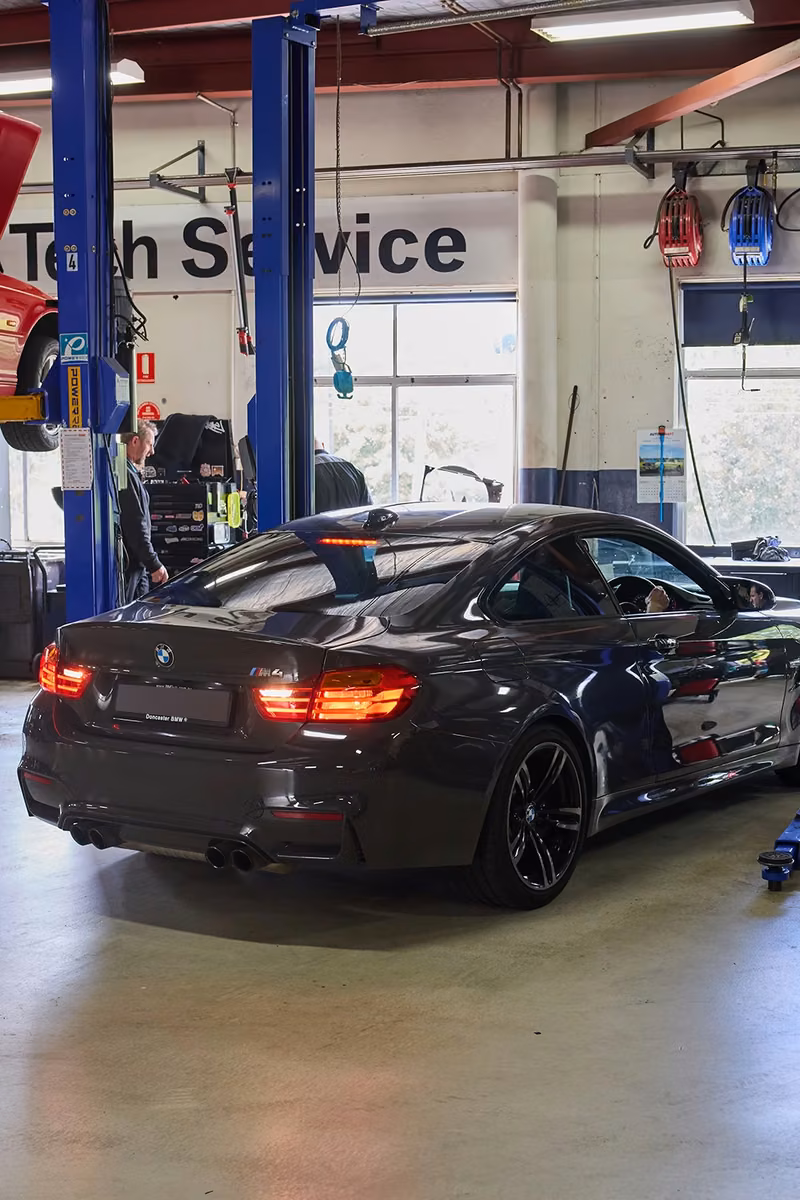BMW parked in the BMT Workshop with a car on a lift in the background