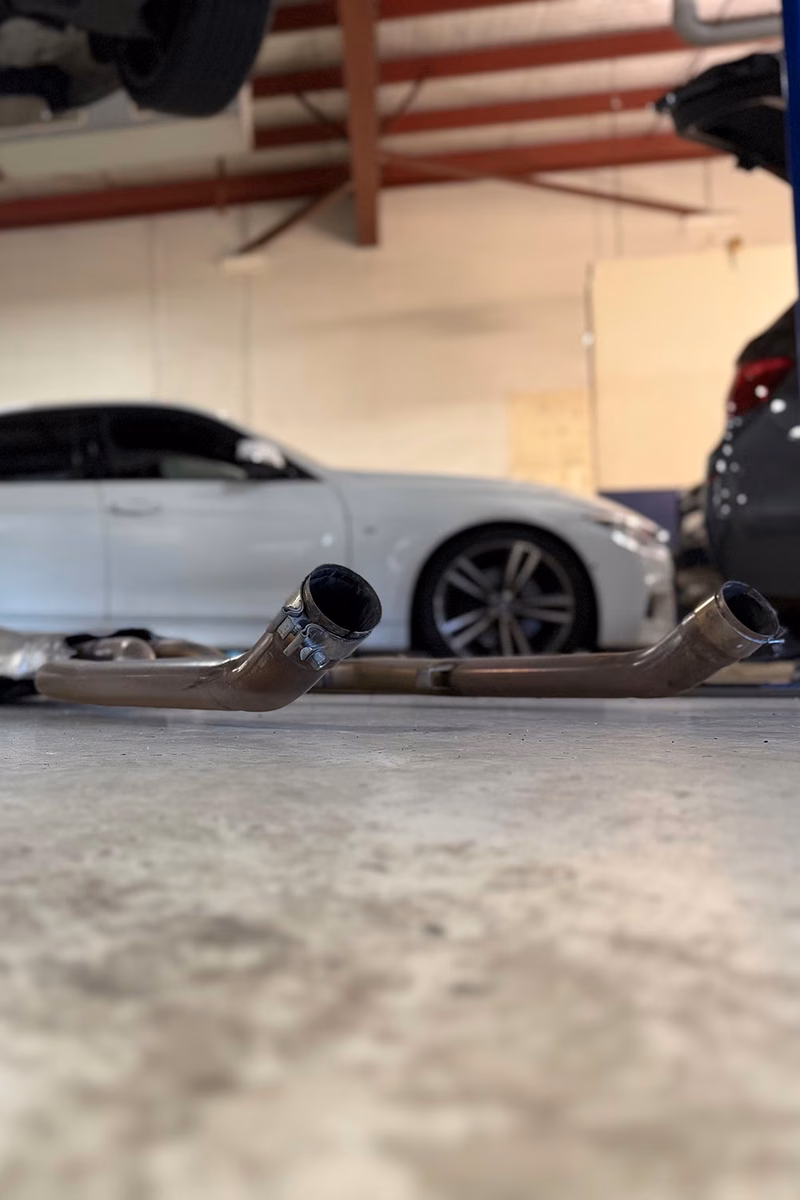 Exhaust pipes on the workshop floor with cars in the BMT Workshop