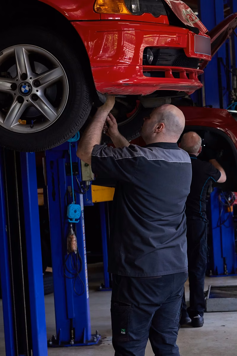 BMT Technician servicing a BMW raised on a lift in the BMT Workshop