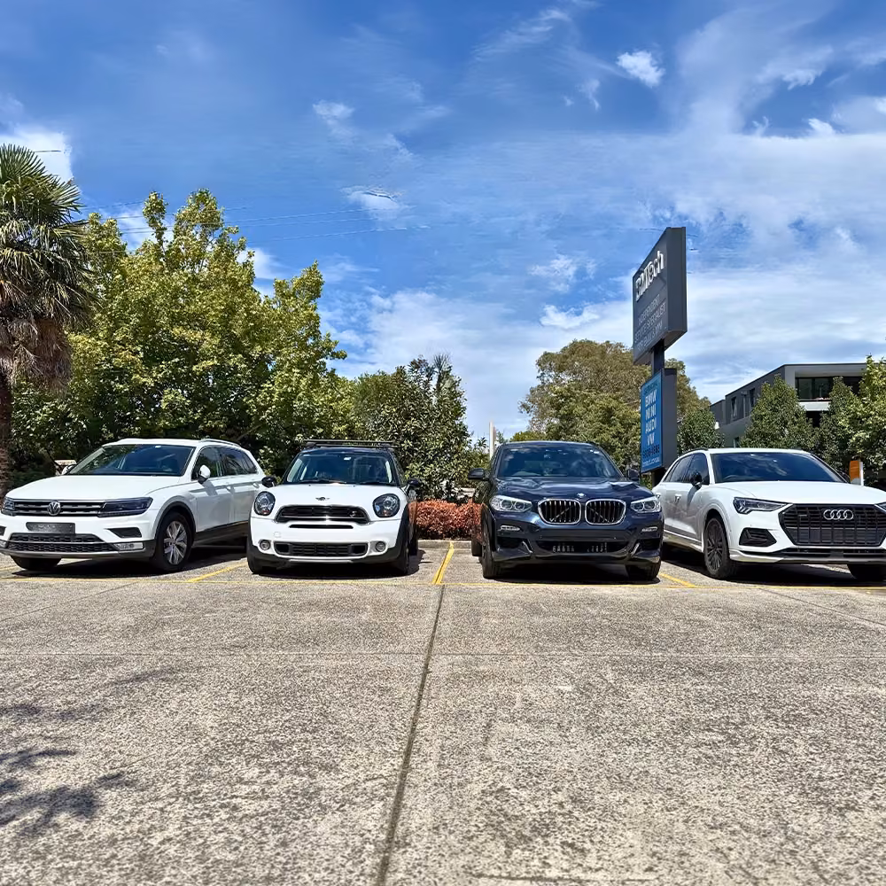 Volkswagen, MINI, BMW and Audi vehicles parked side by side outside an automotive workshop.