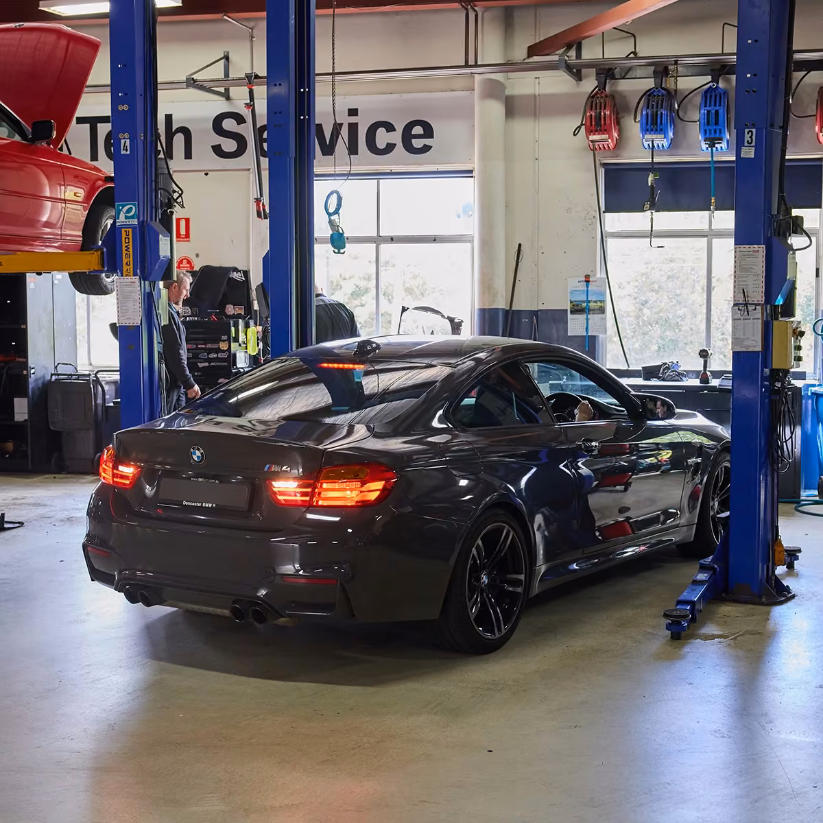 Mechanics working on vehicles using workshop equipment during service
