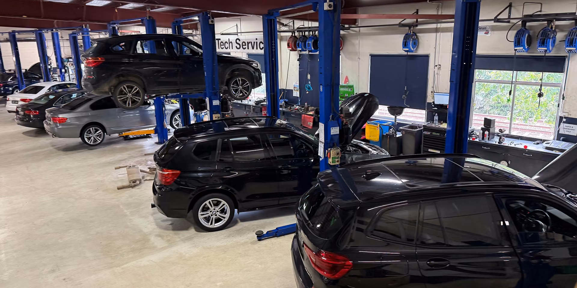 Auto technician servicing car air conditioning system and checking refrigerant levels.