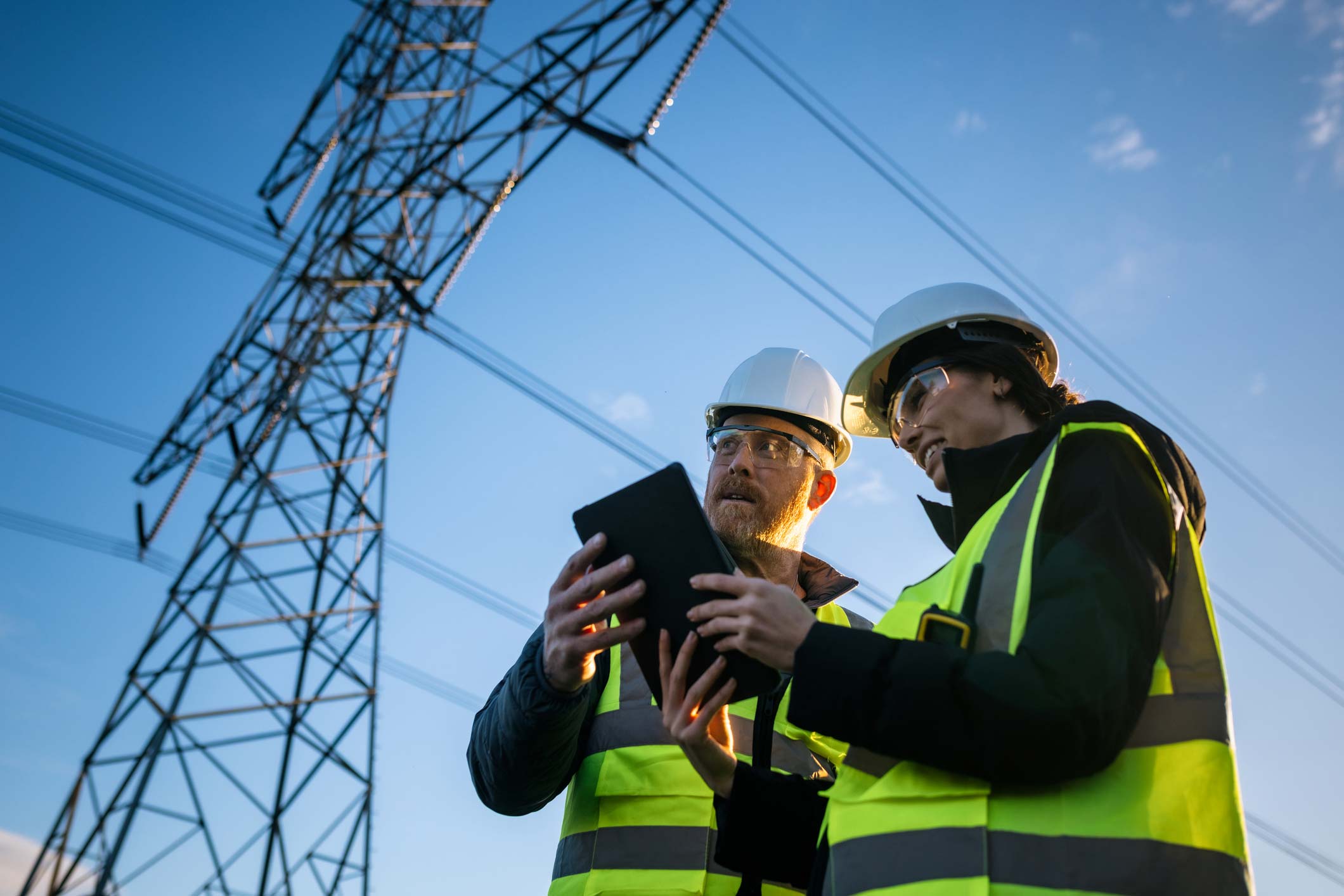 Engineers working beneath a high-voltage transmission tower