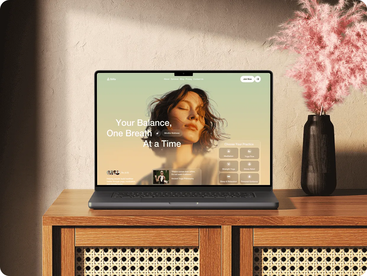 Laptop on wood table showing wellness website with woman's face and mindfulness options, pink flowers nearby.