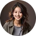 Smiling woman with long dark hair wearing a gray top and blazer against a blurred background.