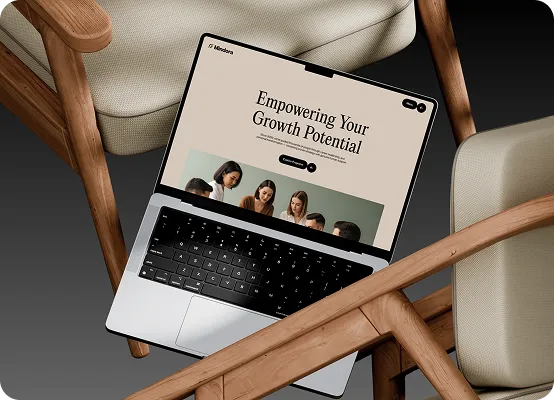 Open laptop on wooden armchairs showing website titled Empowering Your Growth Potential with group photo.