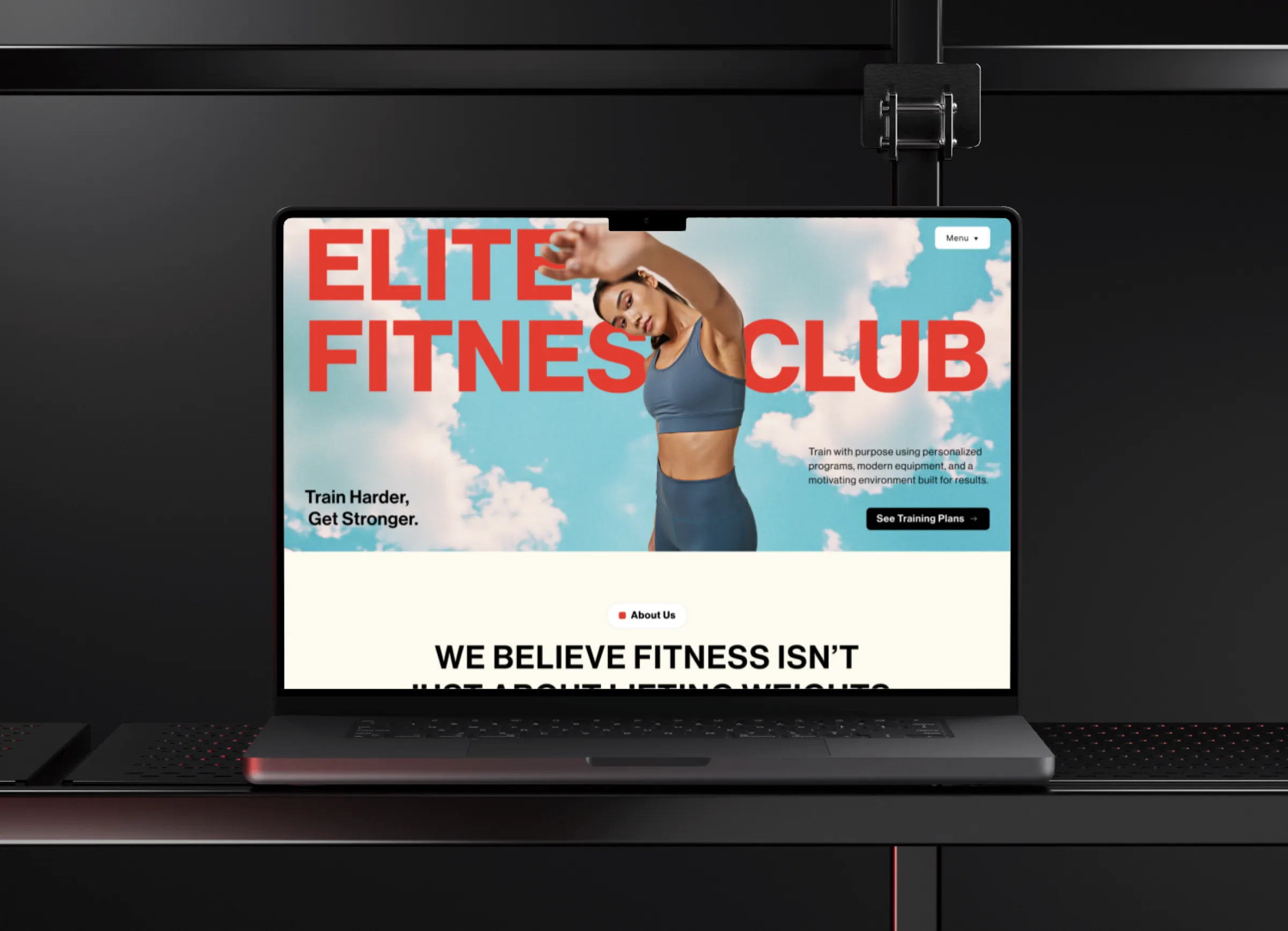 Laptop screen showing Elite Fitness Club website with a woman stretching under a blue sky with clouds.