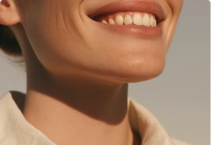 Close-up of a smiling person's mouth and chin with natural lighting and a beige collar.