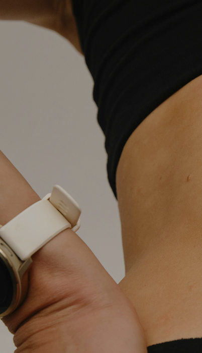 Close-up of a person wearing a black top and a white wristwatch on their left wrist.