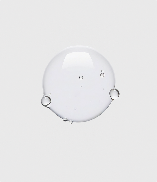 Clear water droplet with smaller bubbles inside on a plain light gray background.