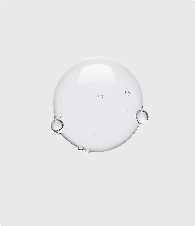 Clear water droplet with smaller bubbles inside on a plain light gray background.