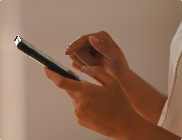 Close-up of hands holding and tapping on a smartphone with a blurred background.