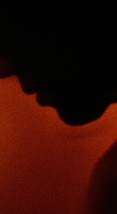 Silhouette of a person’s face in profile against a grainy orange background.