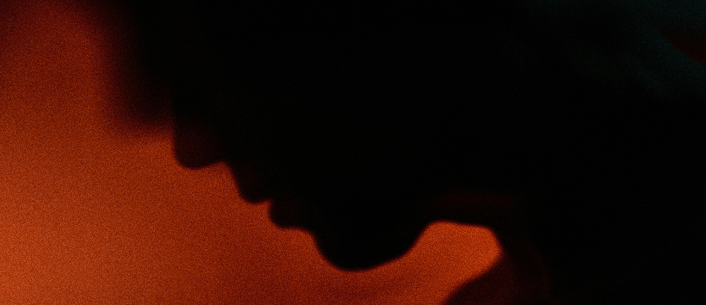 Silhouette profile of a person against a textured orange background.