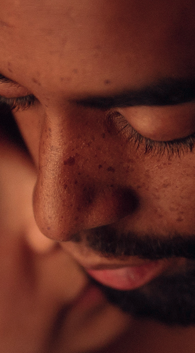 Close-up of a man's face showing his eyes closed and textured skin with freckles.