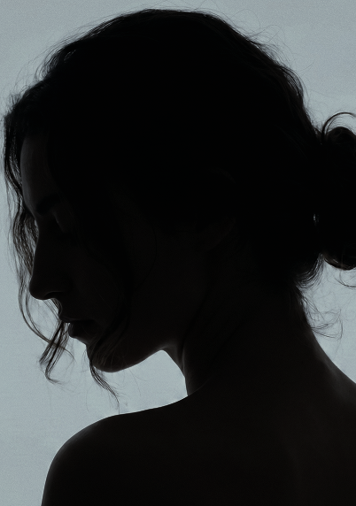 Silhouette of a woman in profile against a light background with hair tied back.