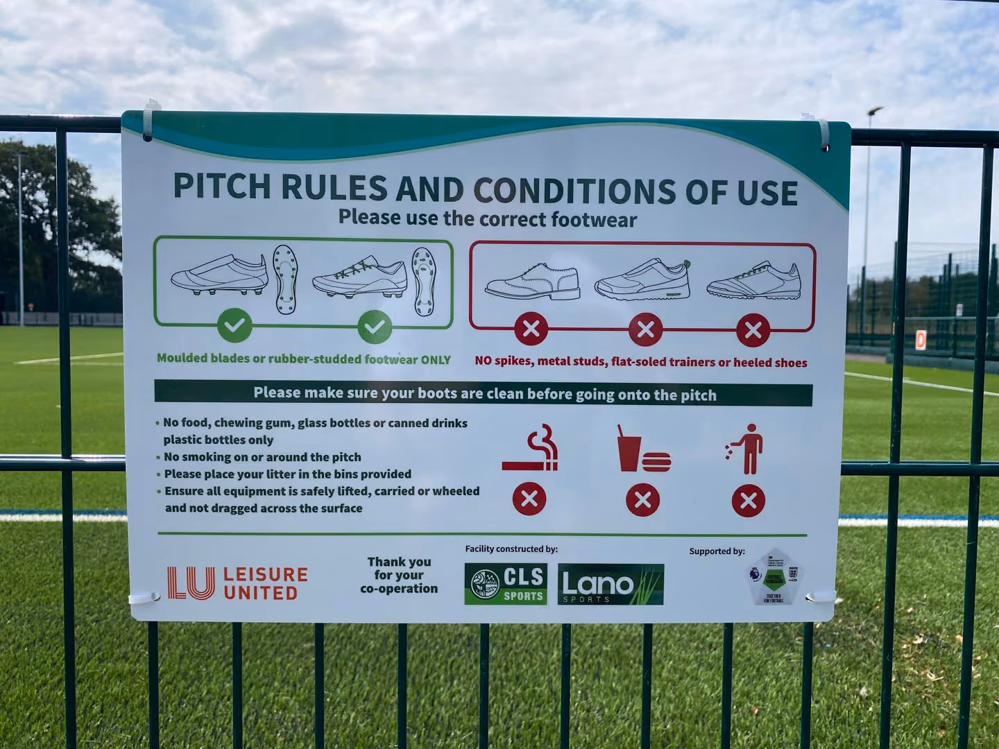 Sign displaying pitch rules and conditions of use, footwear requirements, and facility guidelines on sports field.