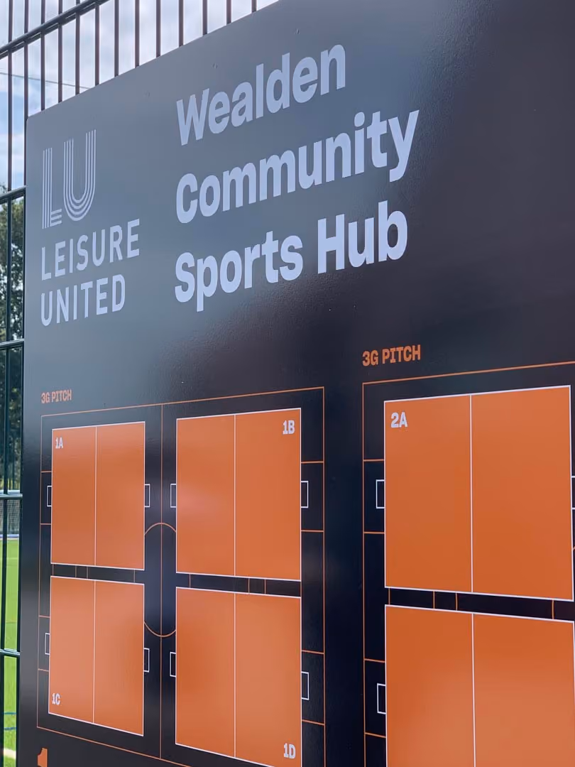 Wealden Community Sports Hub sign with Leisure United logo and orange sports pitch diagrams displayed