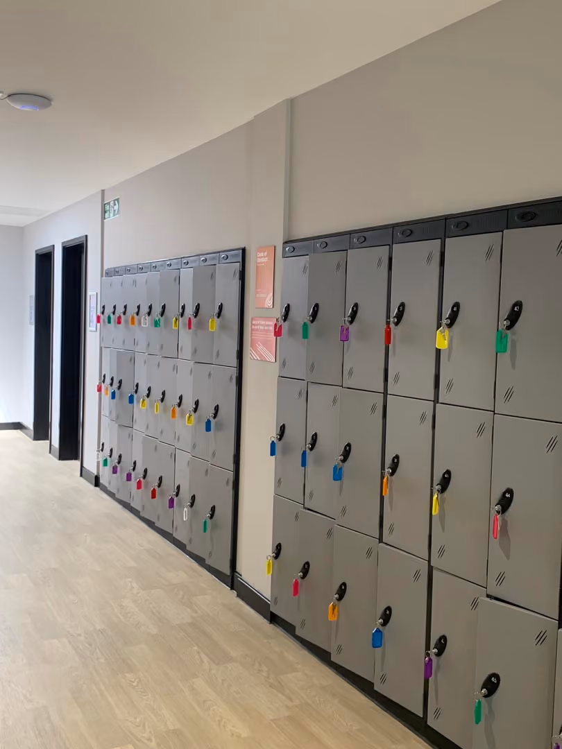 Row of gray school lockers with colorful padlocks in a hallway corridor