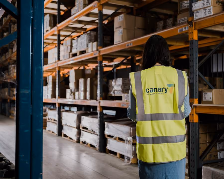Warehouse worker in Canary7 safety vest using technology in a warehouse