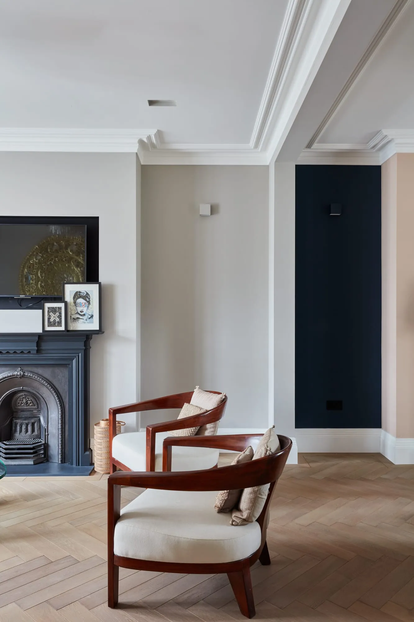 Living room with a period fireplace, herringbone oak floor and a curved timber armchair