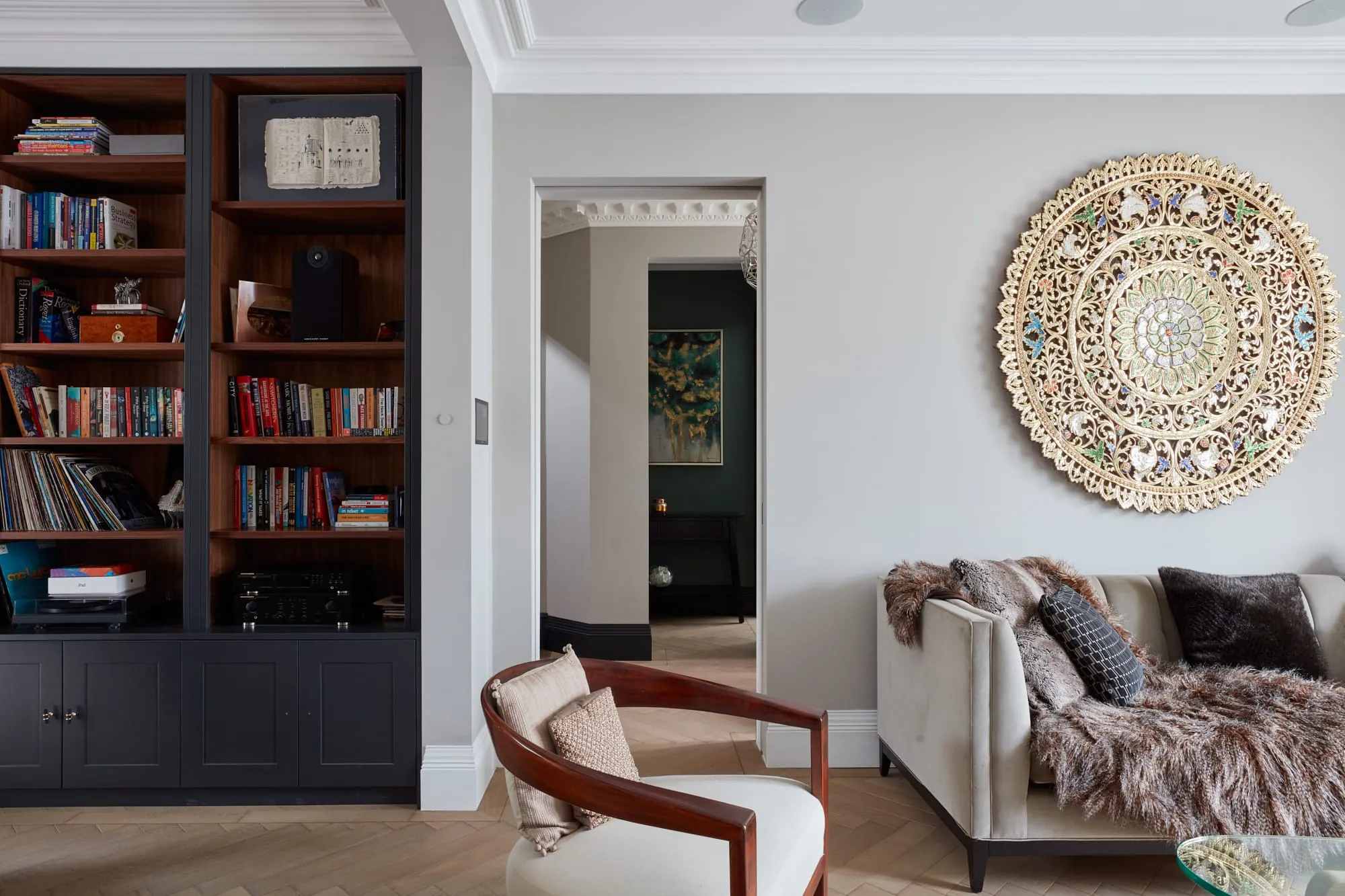 Living room with built-in bookshelves, a carved wall medallion and herringbone floor