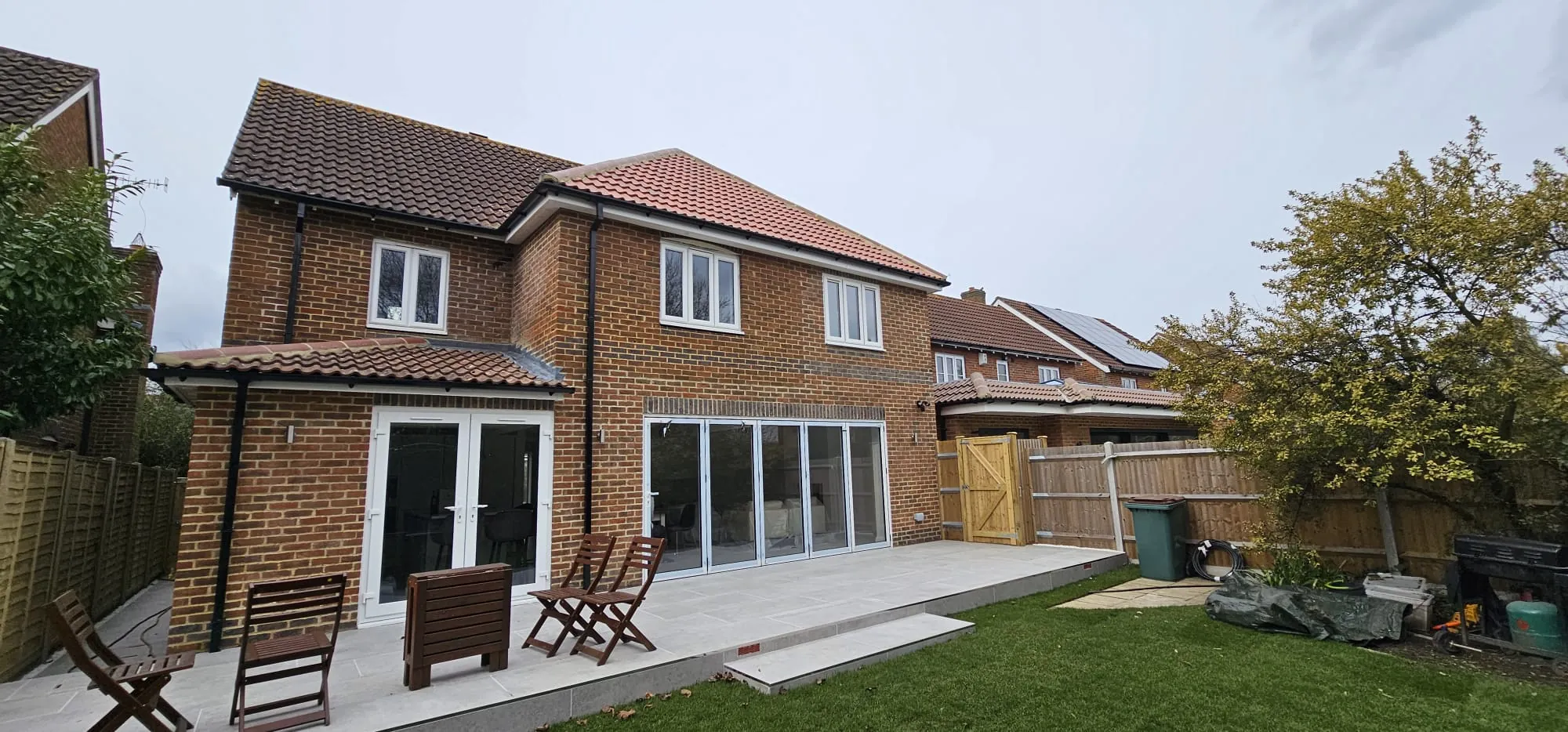 Rear of a brick house with a single-storey extension, bifold doors and a new patio