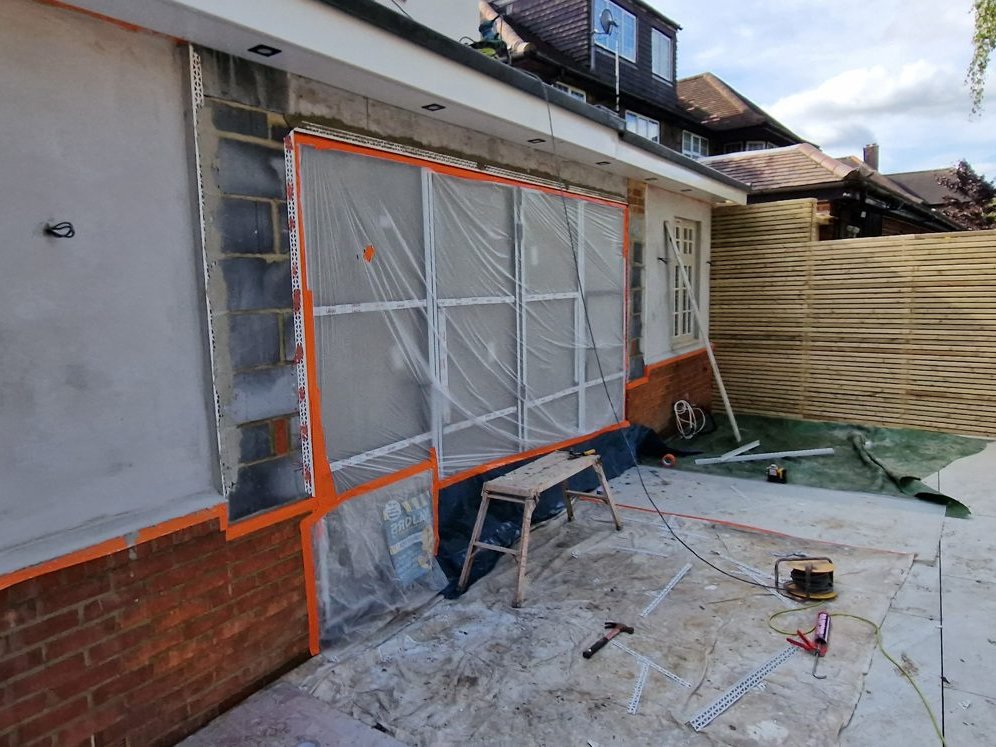 Rear wall being rendered, with the new glazed doors masked in plastic and orange tape