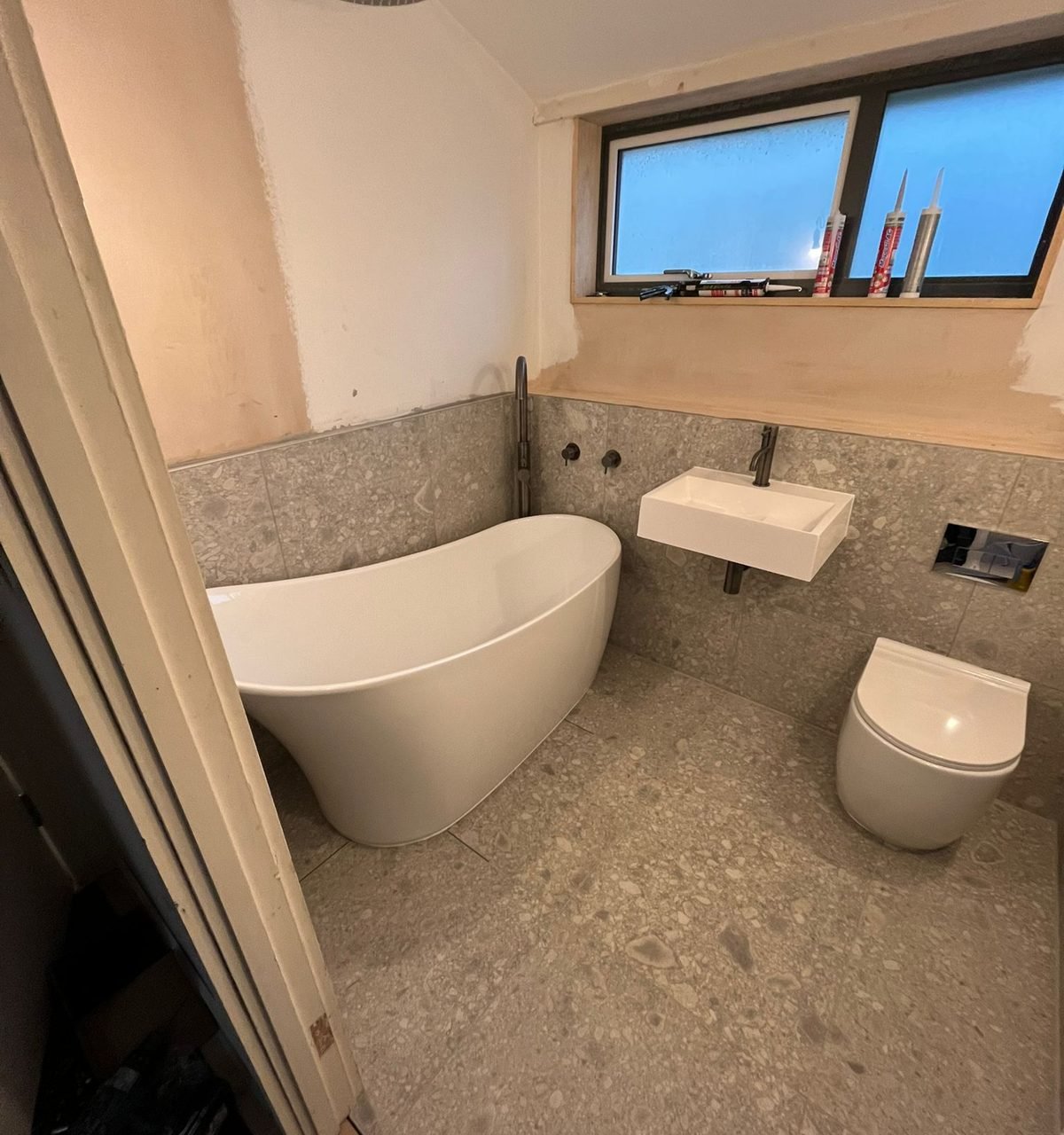 Bathroom with a freestanding bath, terrazzo-effect tiles and a wall-hung basin and WC