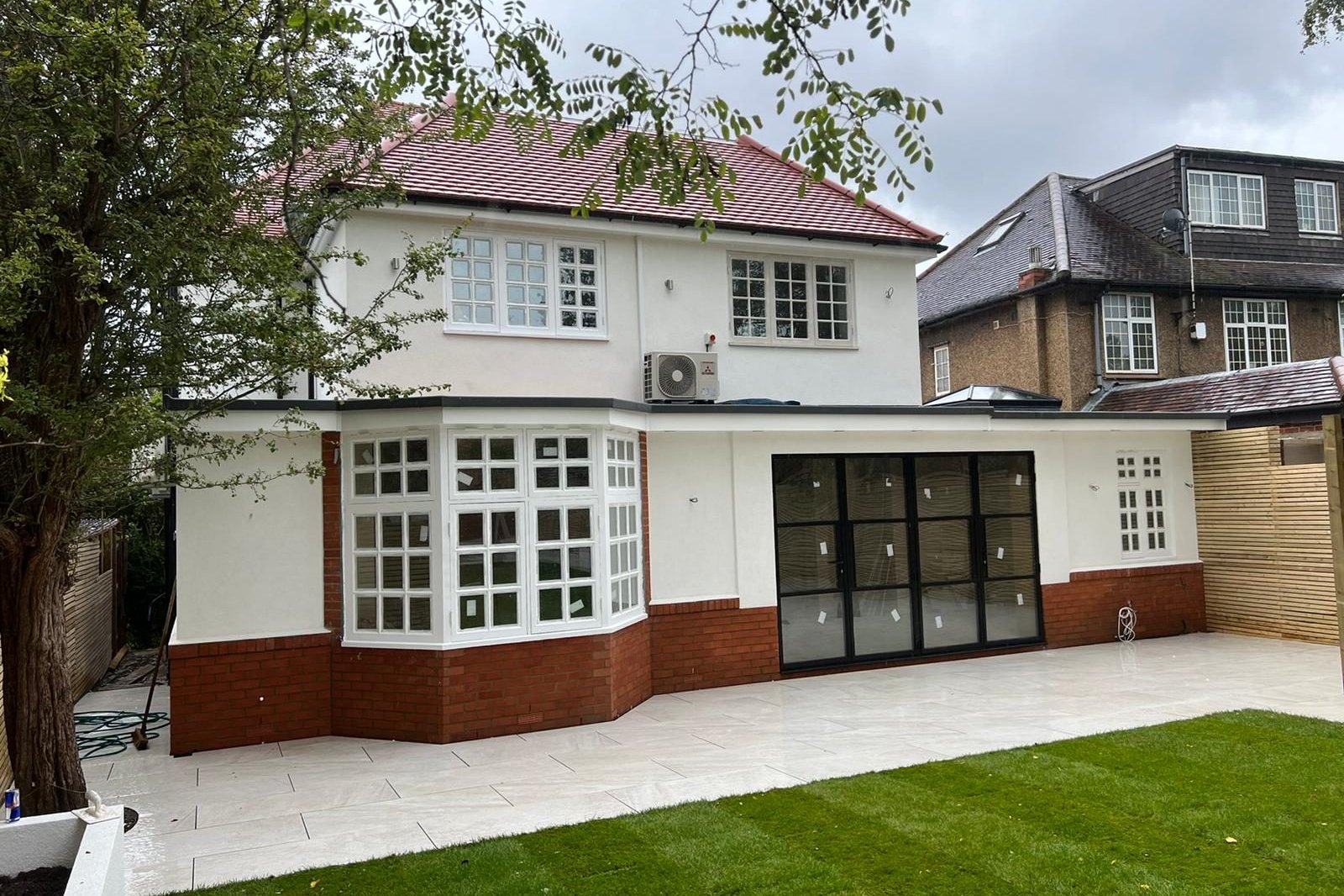 The rebuilt rear of the Ealing house, with new render, a wraparound extension, steel-look glazed doors and a new garden