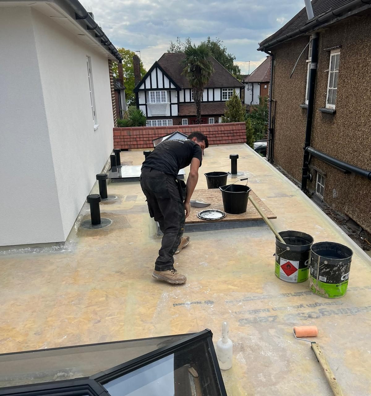 Roofer working on the extension's flat roof between the vents and the roof lantern