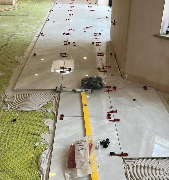Large white porcelain floor tiles being laid with red levelling clips