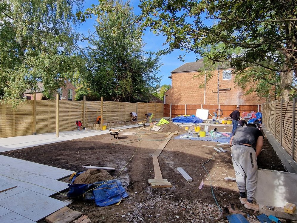 BNS team setting out paths and planters in the bare garden, with new slatted fencing behind