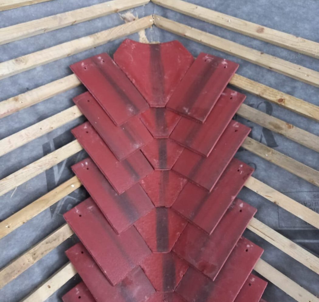 Red clay valley tiles laid in a line down the centre of a roof valley