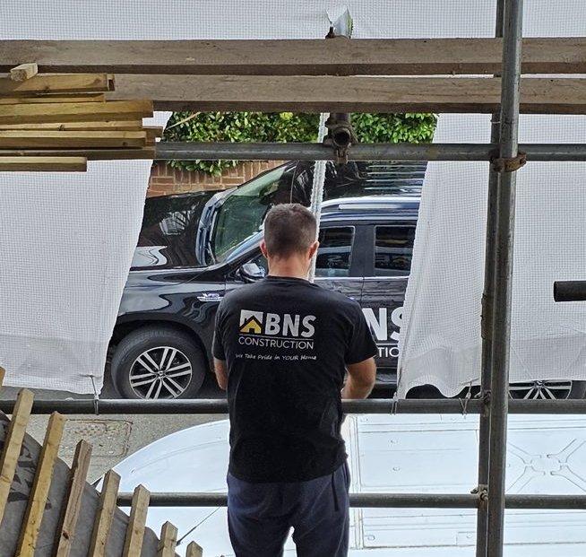 BNS roofer standing on the scaffold, looking down at the street