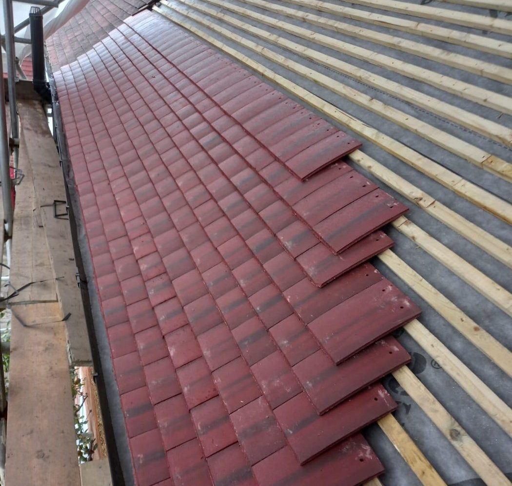 First courses of red clay plain tiles laid over new timber battens