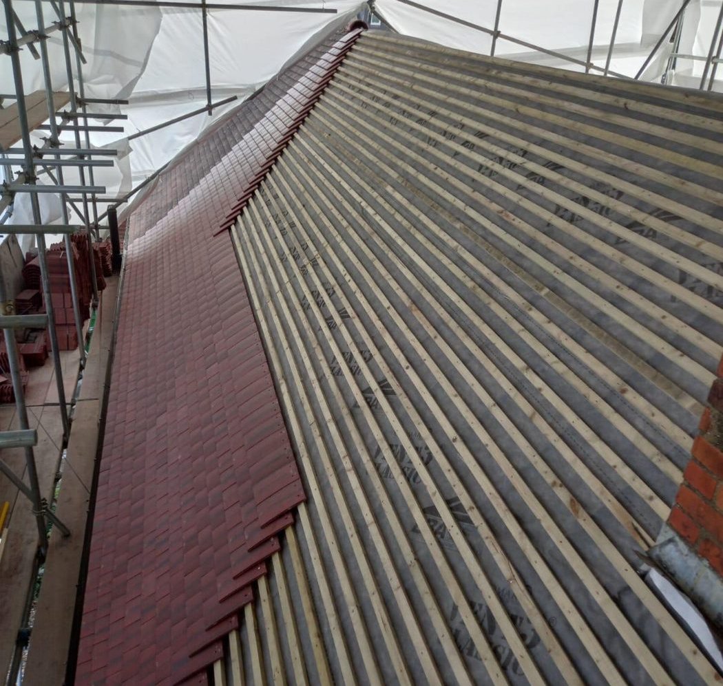 A strip of red tiles running up the slope beside rows of bare battens