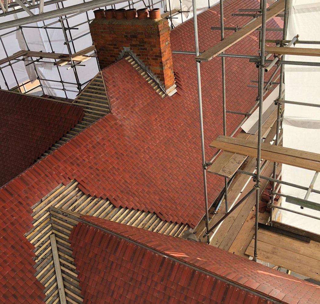 Roof part-tiled, with bare battens still showing around the hips and the chimney