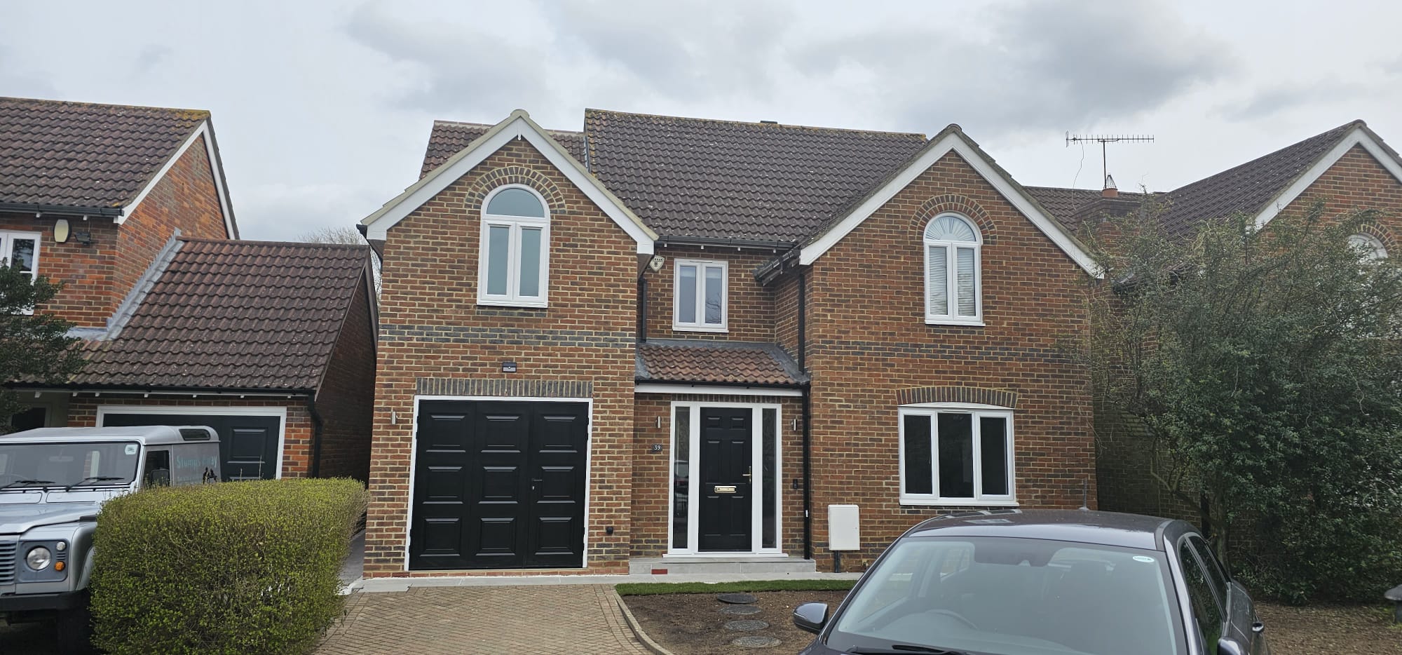 Front of the finished house, with an arched upper window, black garage door and black front door