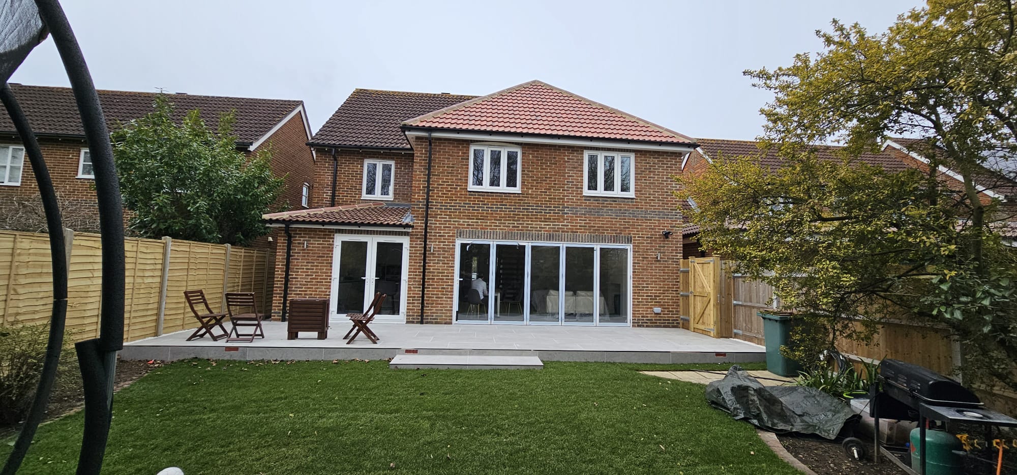 Rear garden and patio, with the two-storey extension in red brick matching the original house