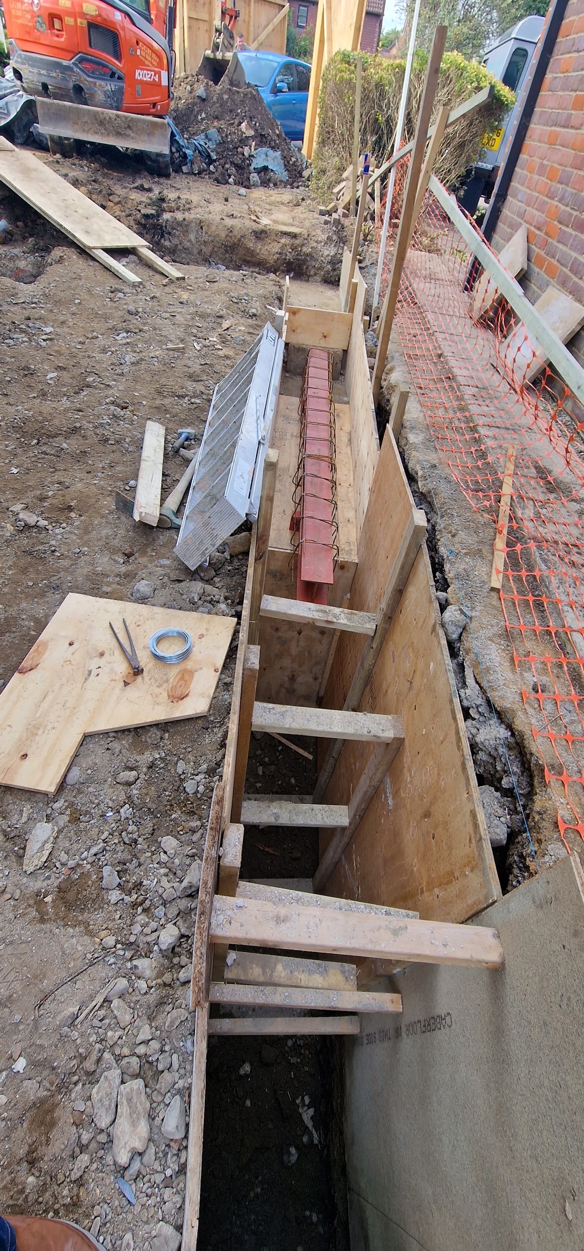 Timber shuttering and props lining the ground beam trench beside the house wall