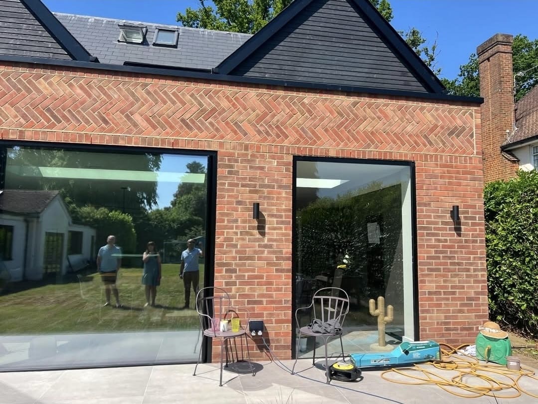Herringbone brick band above two frameless picture windows at the rear of the extension