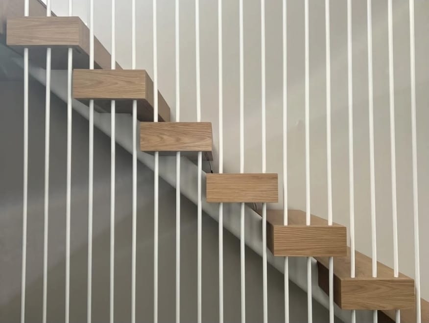 Close-up of solid oak treads fixed into the wall behind white vertical rods